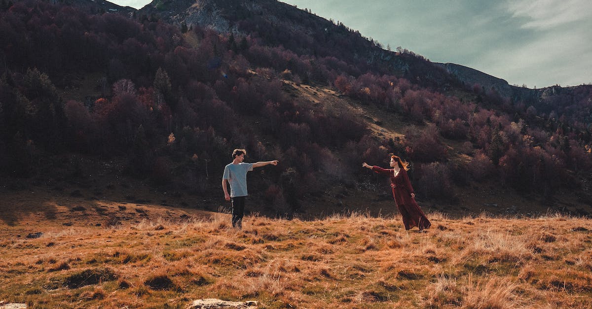 How do these terrain mountains/ledges affect gameplay? - Full body of stylish couple in casual clothes standing in mountainous valley with dry vegetation and reaching hands while looking at each other
