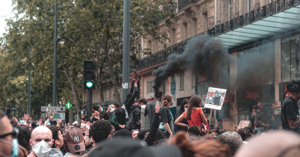 How do units reform formations after disruption? - Anonymous ethnic crowd of people standing on city street with posters and smoke bomb in protest against racism