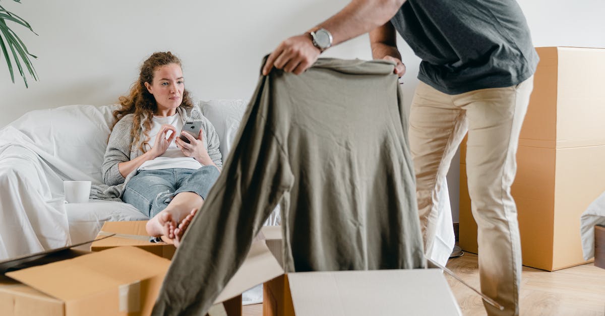How do you get a new house for Michael and Trevor - Crop anonymous male in watch getting polo neck out of cardboard box while standing near pensive barefoot girlfriend sitting with crossed legs on comfortable couch after moving into new flat