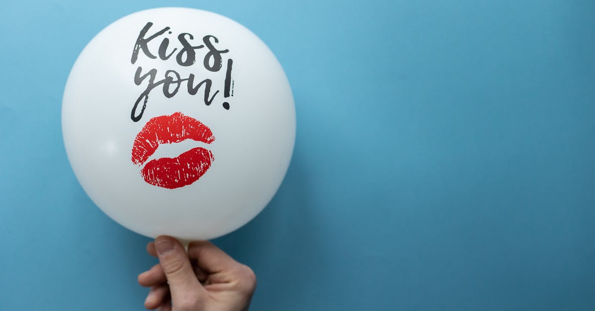 How do you mark components and what effect does it have? - Unrecognizable person demonstrating white balloon with Kiss You inscription and kiss mark on blue background in studio during holiday celebration