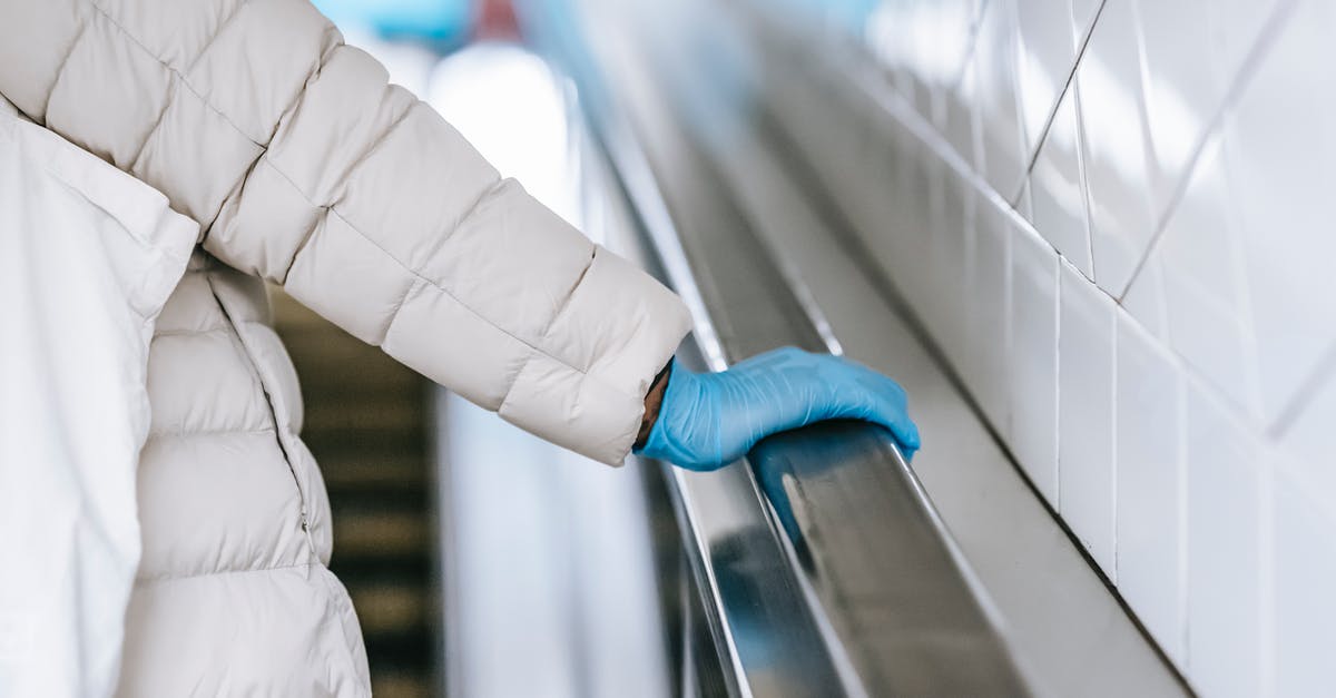 How do you move a tile in OpenTTD - Back view of crop anonymous ethnic female medic in padded coat and latex glove touching handrail of moving stairs in underground