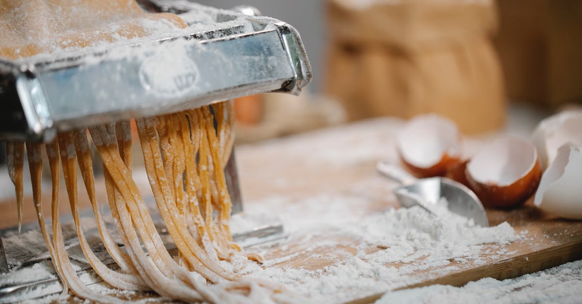 How do you produce iron? - Spaghetti produced from iron pasta cutter on wooden table with eggshell and flour on blurred background