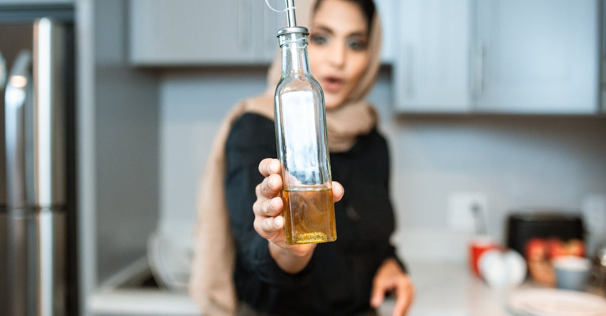 How do you pump Creosote Oil out of a Coke Oven - Ethnic woman demonstrating bottle of olive oil while cooking