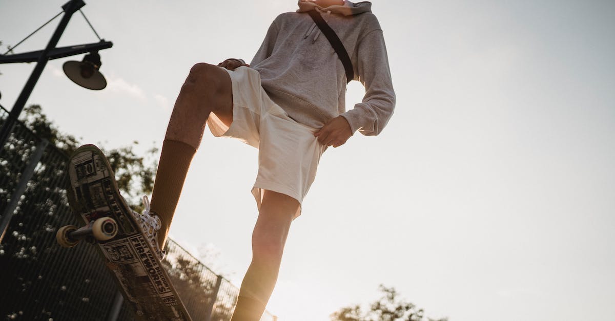 How do you turn on the fast walking ability on Smart Moving Mod? - From below of crop young male in casual outfit standing on skateboard ready to ride on ramp in skate park