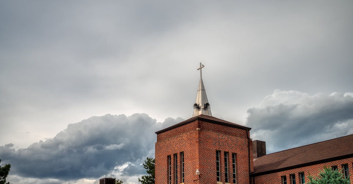 How do you view your town's history when sitting on the wall in the event plaza? - From below of aged brick house on background of dome of church at cloudy day