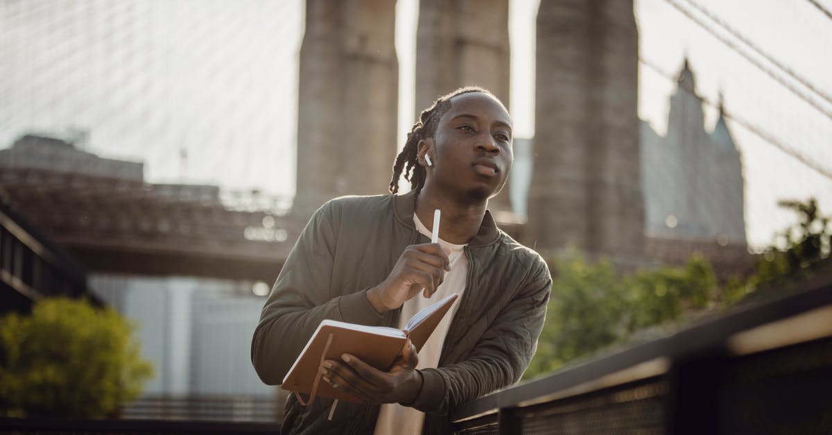 How do you wait until a specific time of day? - Serious African American guy with planner waiting for meting with planner in downtown