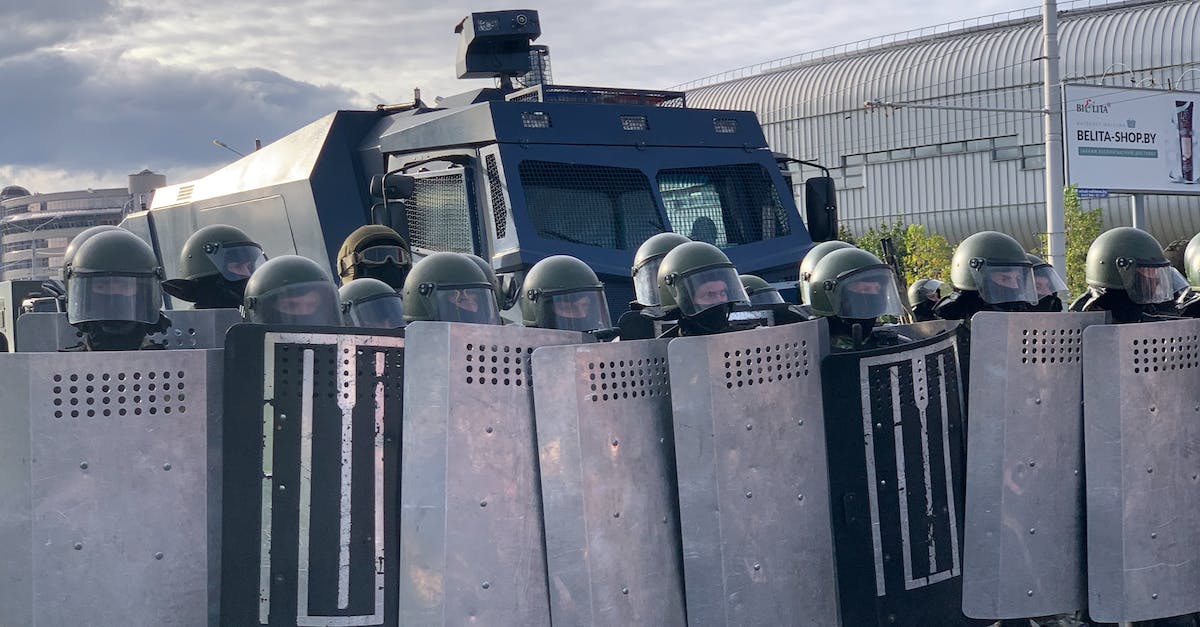 How Does Defense On Helmets Work? - A Group of Soldiers Lined Up with Shields in Front of an Armored Van How Does Defense On Helmets Work? - A Group of Soldiers Lined Up with Shields in Front of an Armored Van