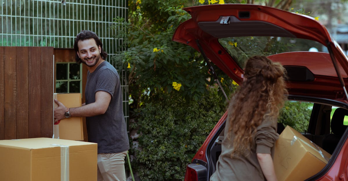 How does item durability affect its performance - Happy couple in casual clothes moving personal items in carton boxes from car trunk to new house
