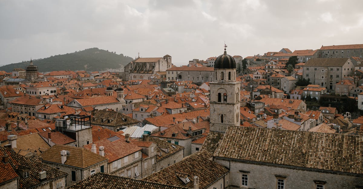 How does skipping ahead to Lothric Castle affect various NPC quests? - Cityscape of old town on hills with stone tower and various houses with tiled roofs in overcast weather
