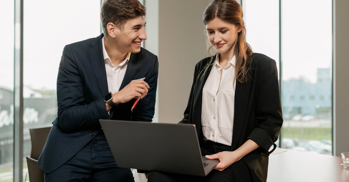 How does supercharging work? - Man in Black Suit Jacket Holding Black Laptop Computer Beside Woman in Black Blazer