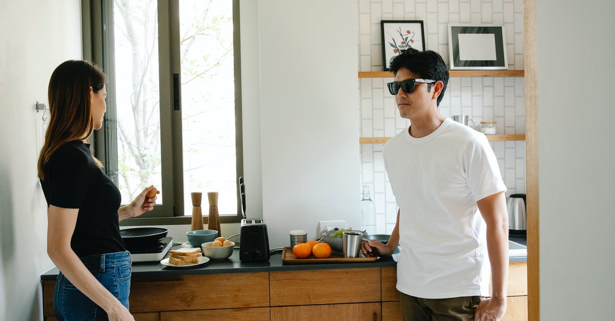How does the Anglerfish being blind help me avoid them? - Young Asian man with vision loss in black glasses standing in kitchen with wife preparing breakfast while spending morning together at home