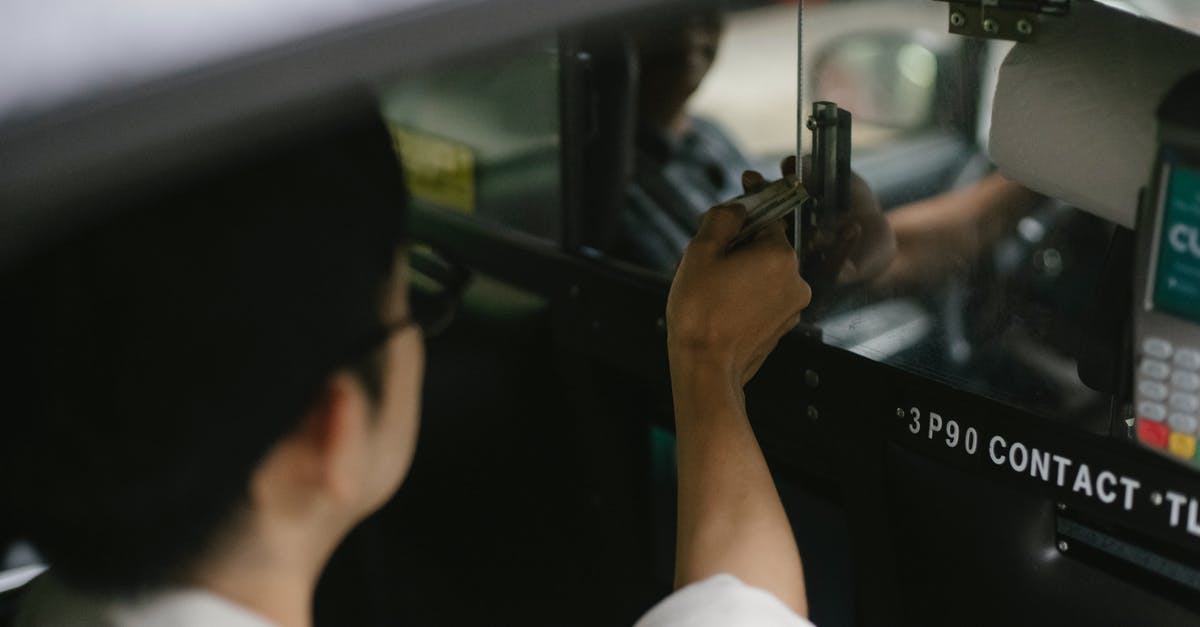 How does the Auto selection work? - High angle of crop young male passenger in white shirt sitting in automobile and giving dollars to driver