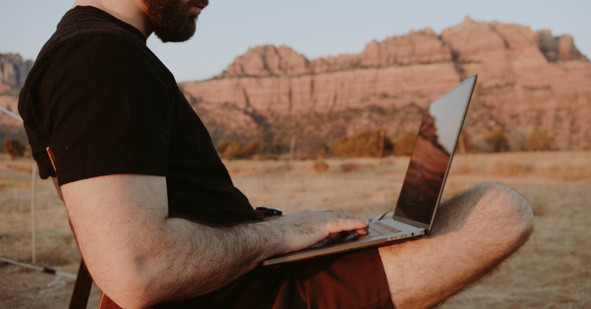 How does the Hunter Rank Range work? - Side view of crop male freelancer sitting on chair while working on laptop in desert with mountain range