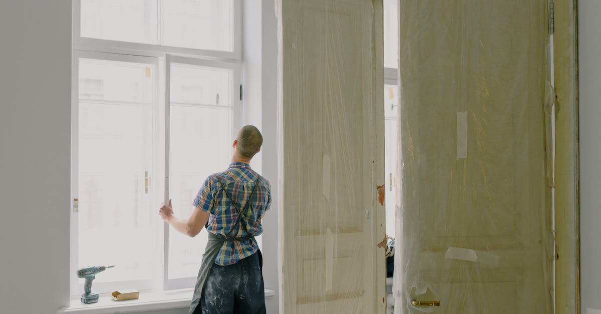 How does the new trait system work? - Back view of unrecognizable workman in apron mounting window near drilling machine and doors in flat