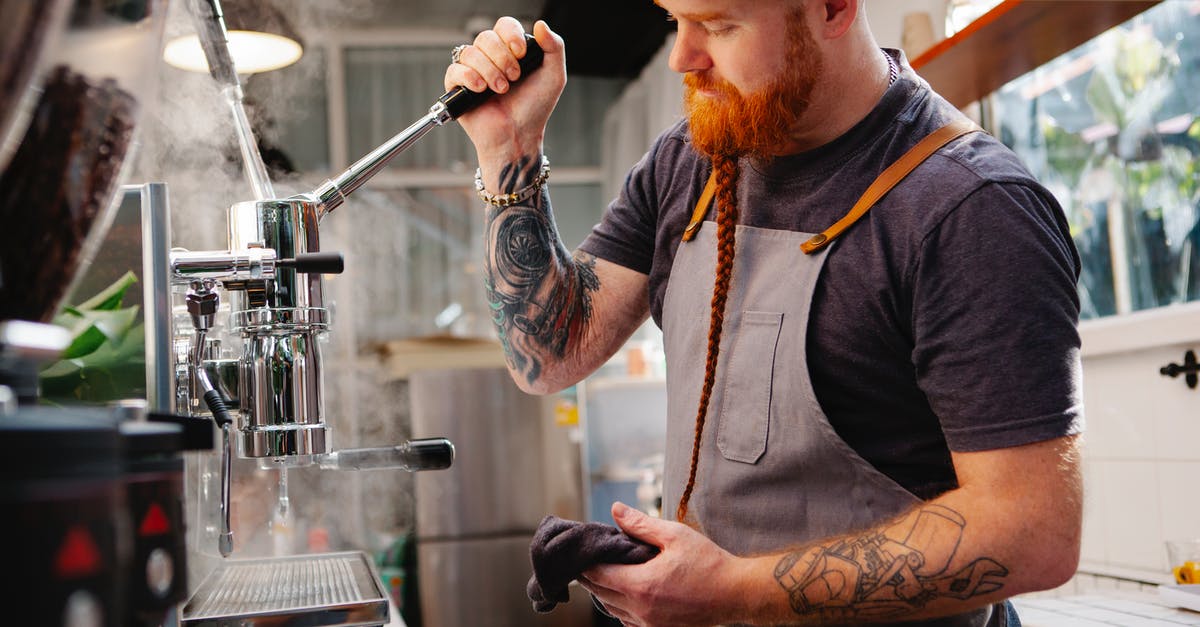 How does the swtor subscription work in steam? - Side view of tattooed male with beard wearing cap standing near coffeemaker with lever and steam while working in coffee house