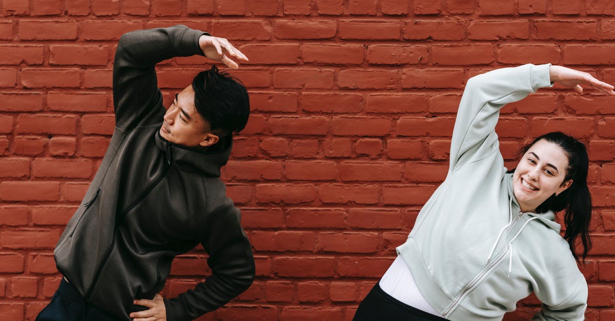How does the trainer level affect powering up Pokemon? - Positive young plus size female and fit Asian male trainer standing near brick wall and doing Overhead Side Reach Stretch exercise before workout on street How does the trainer level affect powering up Pokemon? - Positive young plus size female and fit Asian male trainer standing near brick wall and doing Overhead Side Reach Stretch exercise before workout on street