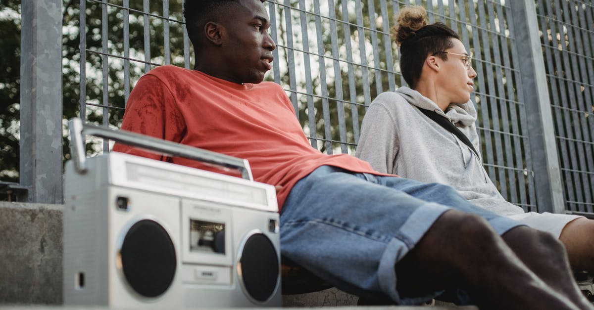 How far away do I need to be away from guards and sound bugs to avoid being heard? - Diverse friends with boombox resting near fence in park How far away do I need to be away from guards and sound bugs to avoid being heard? - Diverse friends with boombox resting near fence in park