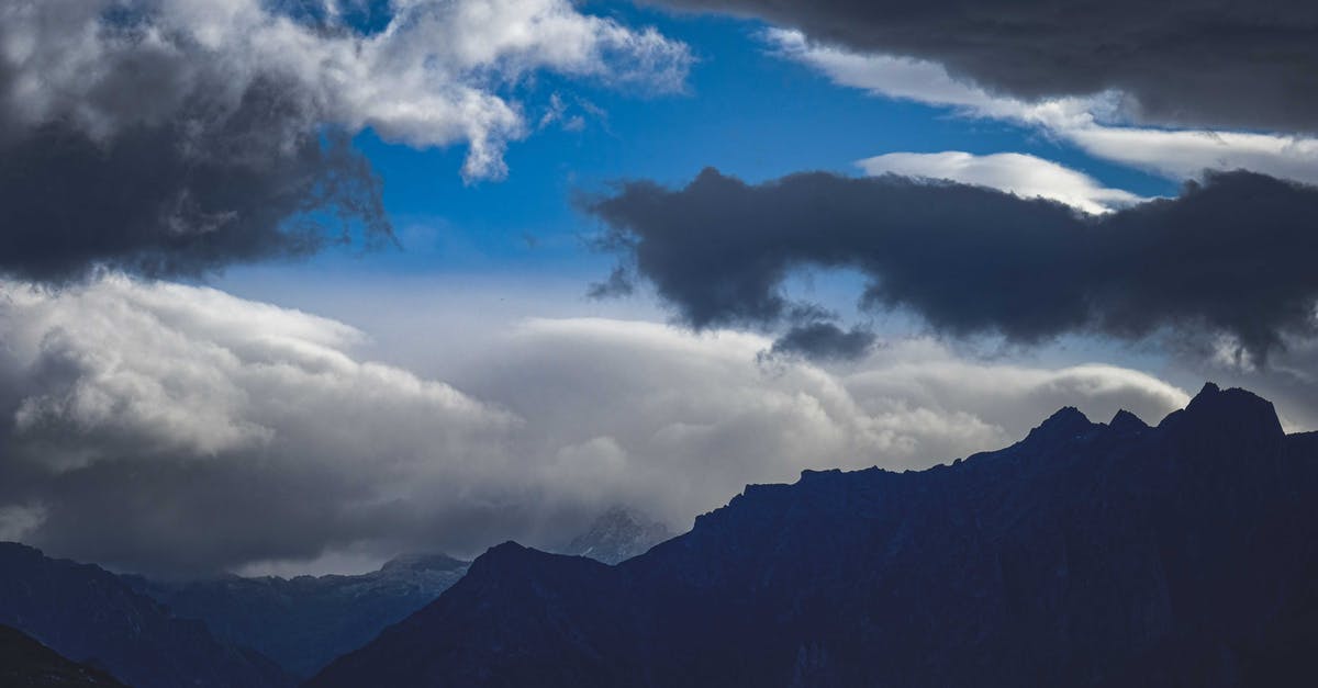 How far does the range of magic go? - Picturesque view of majestic mount silhouettes with peaks under blue sky with fluffy clouds in evening How far does the range of magic go? - Picturesque view of majestic mount silhouettes with peaks under blue sky with fluffy clouds in evening