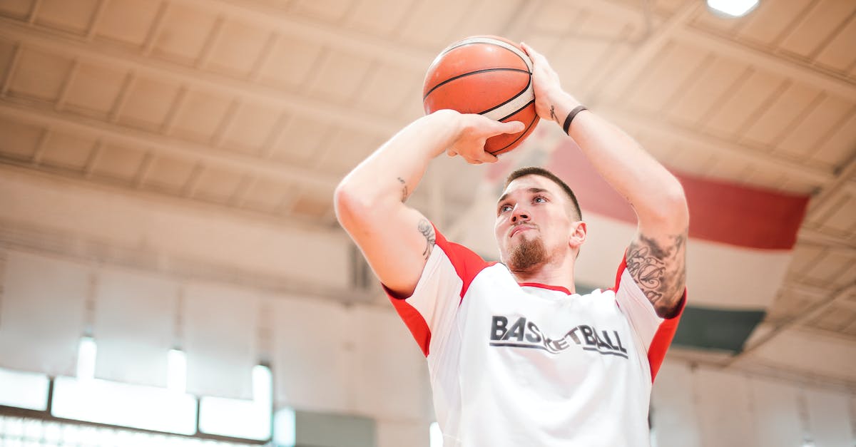 How high can a player go? - From below of concentrated basketball player with tattoos on arms preparing throwing ball to hoop