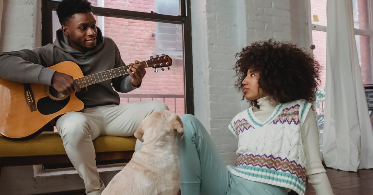 How is morphed skill mastery affected by a reset? - Cheerful black man playing guitar for girlfriend and dog at home