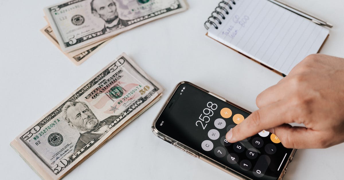 How is the amount of loot calculated at the end of each battle? - From above of crop anonymous economist calculating total amount of income using calculator app on cellphone near piles of greenbacks and notebook with pen