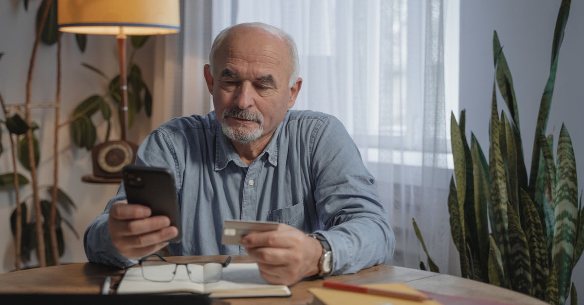 How long are steam purchases valid? [duplicate] - An Elderly Man Using His Mobile Phone while Holding a Credit Card