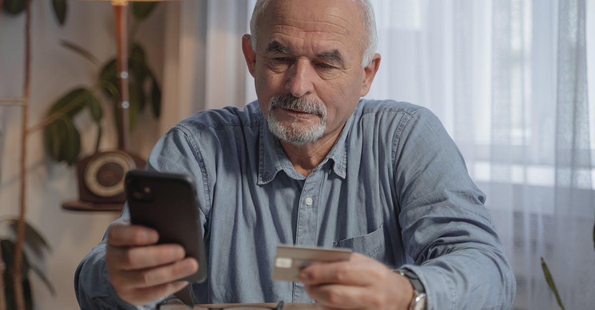 How long are steam purchases valid? [duplicate] - An Elderly Man Holding His Mobile Phone and a Credit Card