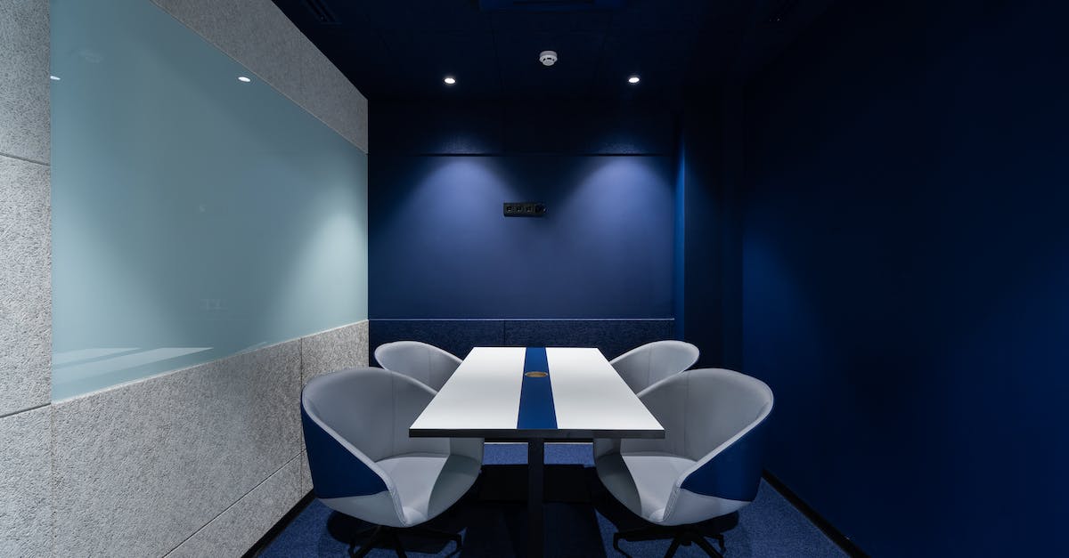 How long can it take to 'repair' a room? - Comfortable chairs placed on carpet at long white desk in modern conference room with blue walls in contemporary business center