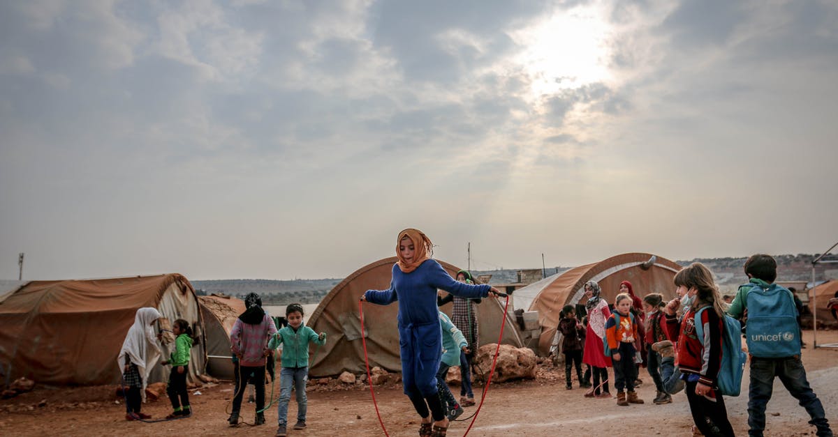 How many agents are active characters? - Full body of many poor children walking and talking near tents under sunny cloudy sky