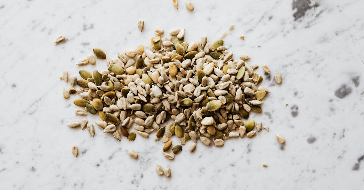 How many perfect pandora seeds exist? - From above of oval shaped dried pumpkin seeds with green and gray shell spilled on marble surface with spots