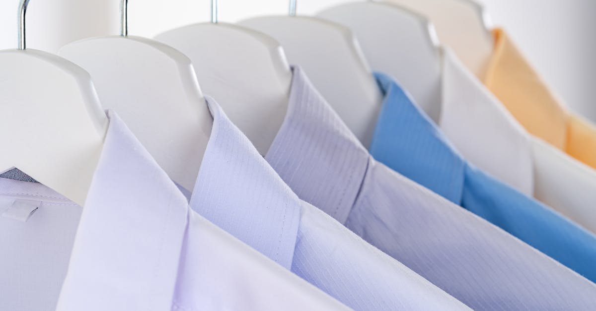 How many pieces of armor and clothing can you wear? - Different elegant shirts for men with collars hanging on identical racks in clothing store on white background