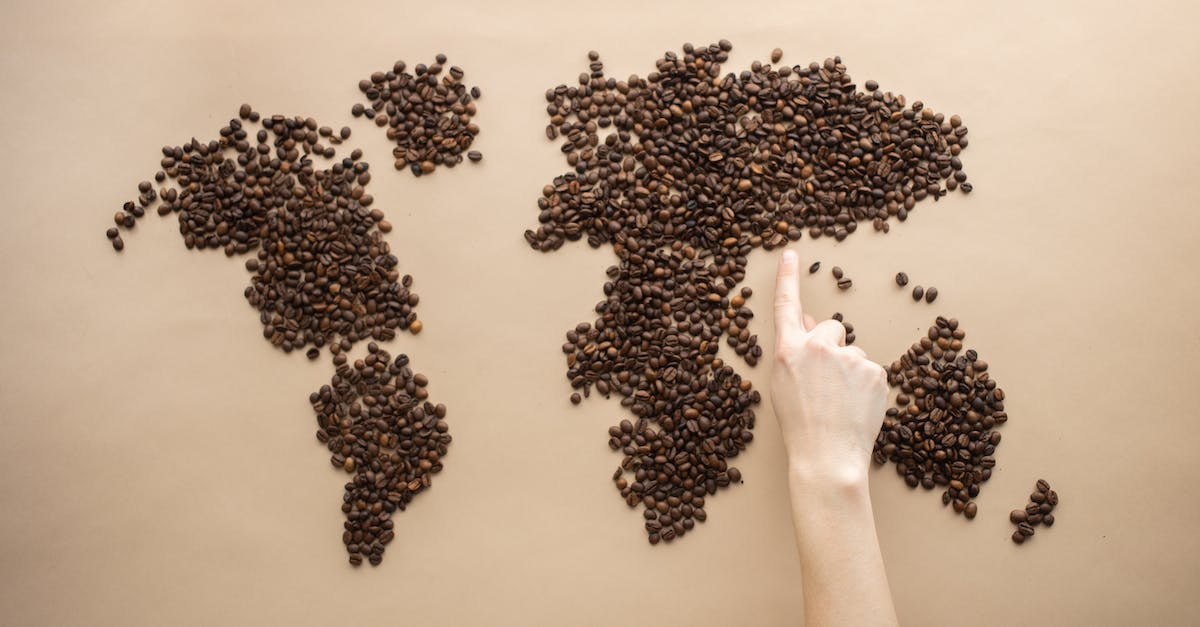 How many points are required to earn medals? - Top view of crop person pointing finger at world map made of coffee beans on brown background