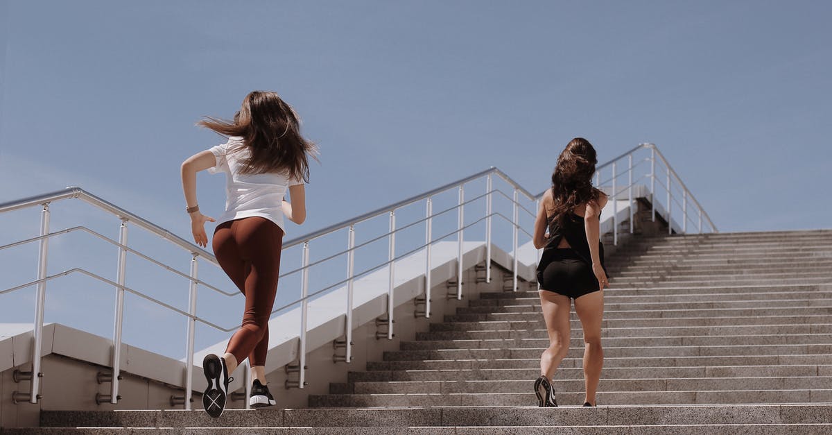 How many steps is one run around Prism Tower? - 2 Women Walking on Gray Concrete Bridge
