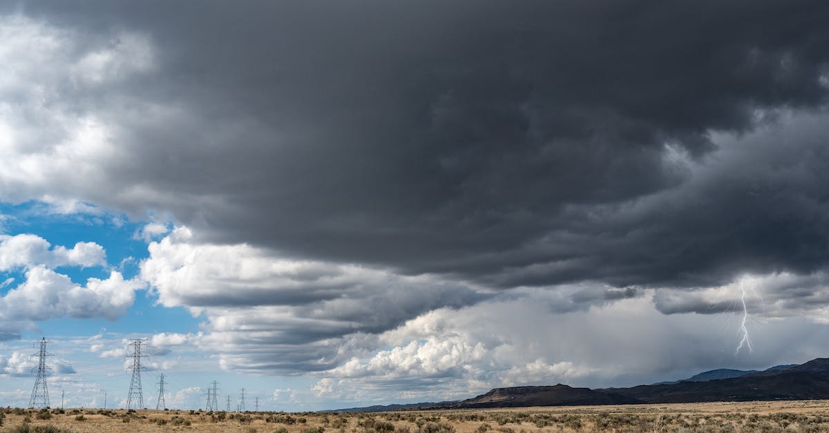 How many times can I upgrade my lightning spell? - Breathtaking view of thick dark clouds on sky with lightning above uneven field with growing plants near metal towers and mountains in gloomy weather