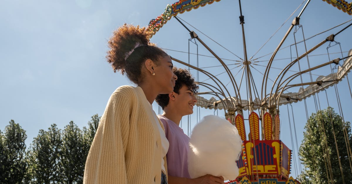 How much candy for walking Pokemon? - Teenage couple walking by big carousel and boy holding cotton candy