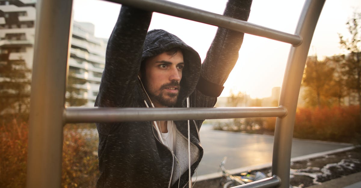 How much energy is produced by connecting a city to my capital - Young athletic male in sportswear with earphones doing exercises on ladder while training on sport ground near river in autumn morning in city
