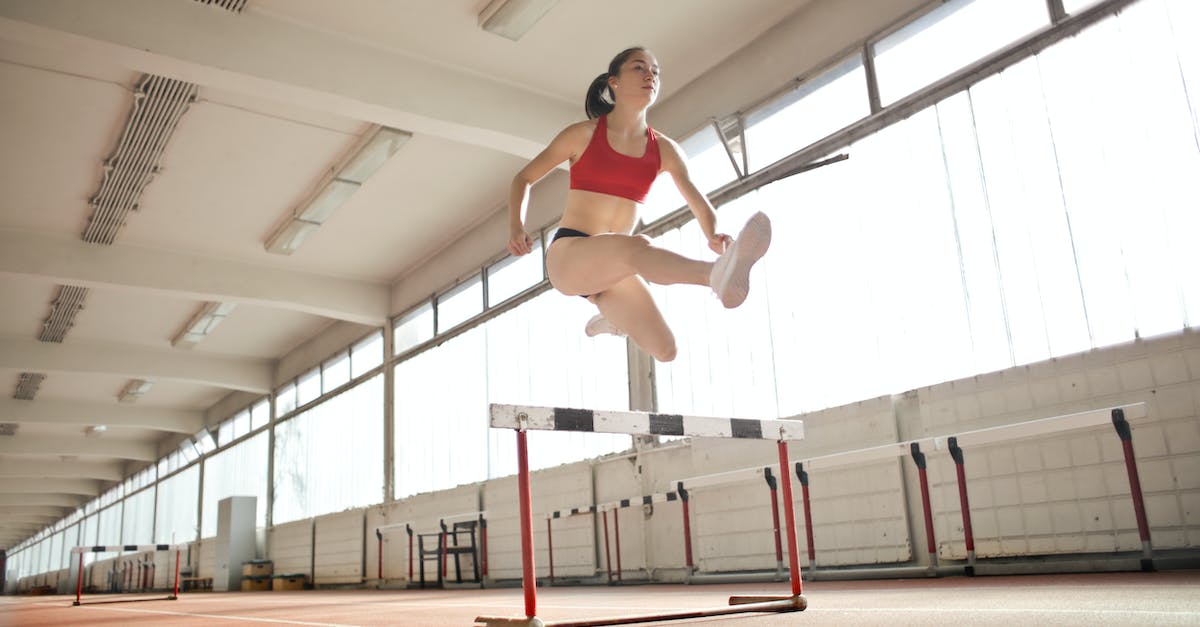 How much faster is jumping while sprinting? - Woman in Red Sports Bra Jumping on White and Black Obstacle