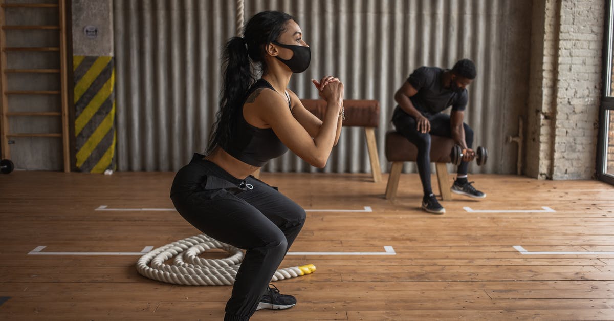 How much prestige does a gym lose when battling it? - African American female athlete and unrecognizable sportsman in fabric masks exercising on floor in gymnasium