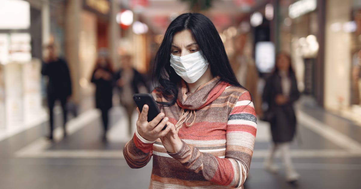 How much space does each world take up? - Young female customer in striped wear and protection mask on face using smartphone while standing in shopping mall during coronavirus pandemic