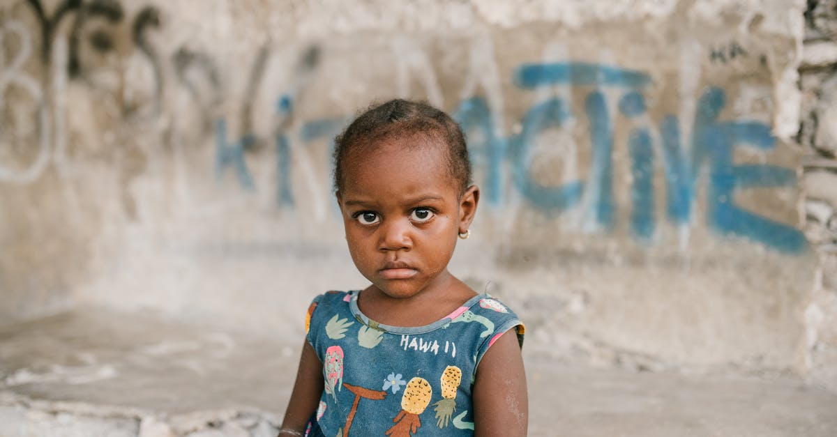 How much status damage (like bleed) do I need to deal to proc the effect (i.e. blood loss)? - Frowning African American girl near weathered concrete building with vandal graffiti and broken wall in poor district