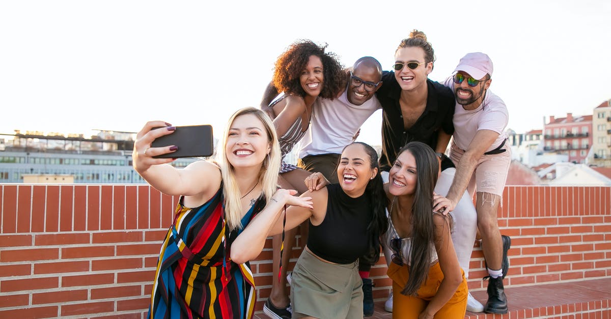 How much time do I have to take a decision about an event? - Group of cheerful young male and female multiracial friends laughing and taking selfie on smartphone while spending time together on terrace
