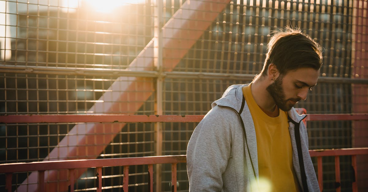 How much unhappiness do puppet cities generate? - Young upset unshaven male in casual apparel looking down near grid fence in back lit in town How much unhappiness do puppet cities generate? - Young upset unshaven male in casual apparel looking down near grid fence in back lit in town