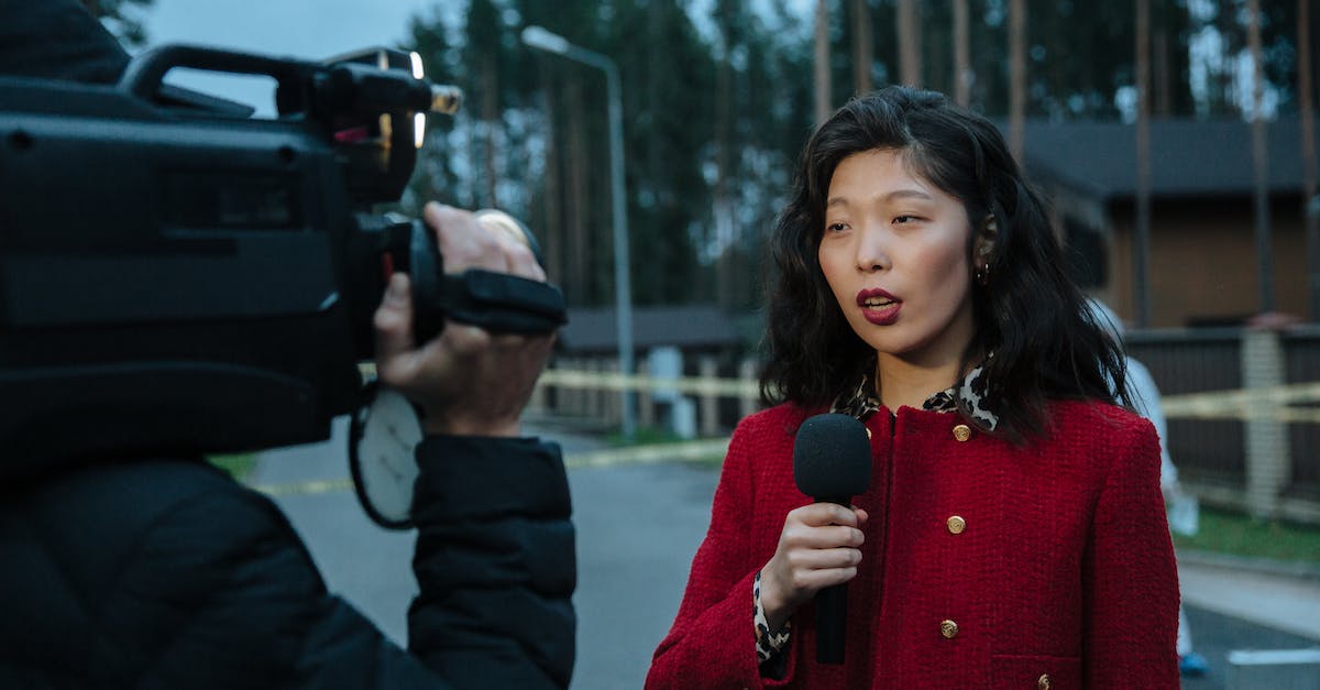 How often do the news broadcasts occur? - Woman in Red and Black Sweater Holding Black Camera