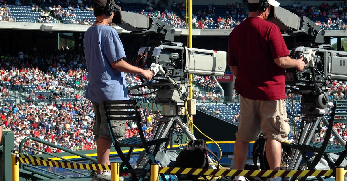How often do the news broadcasts occur? - 2 Camera Man Standing in a Green Metal Stage during Daytime
