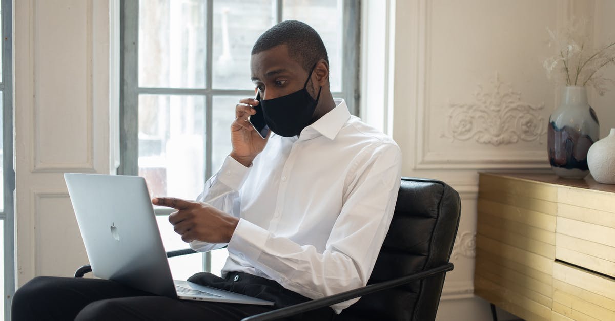 How prevent orbit change while using RCS to point probe anti-radial all time - Black businessman in mask using laptop while talking on smartphone