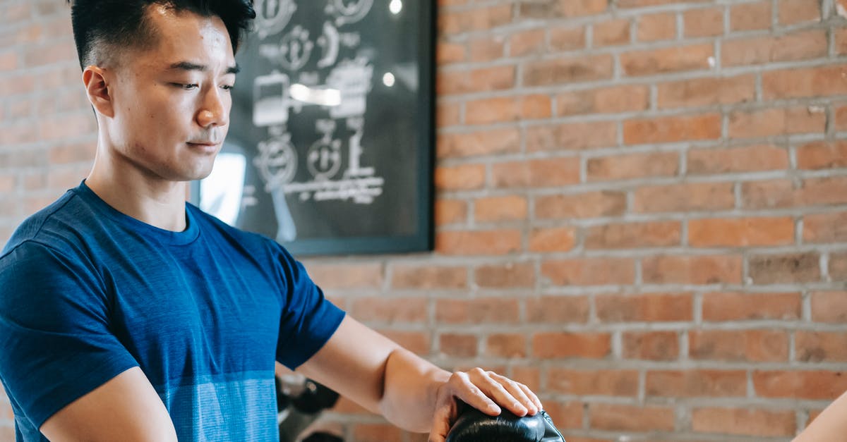 How should I prepare for gym fights? - Serious Asian trainer putting on woman gloves before workout How should I prepare for gym fights? - Serious Asian trainer putting on woman gloves before workout