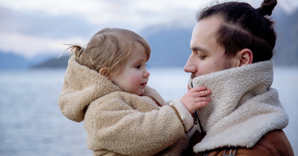 How should I travel to the other regions of Mira? - Satisfied young father and little daughter near sea in cold season