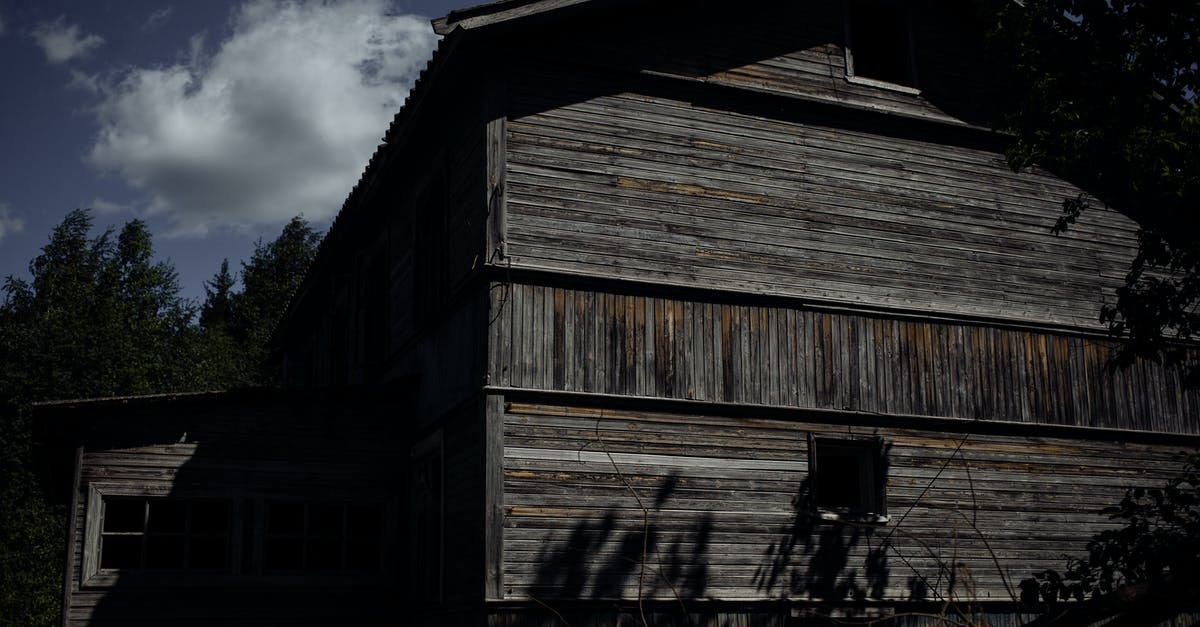 How tall should I build my minecraft mob farm? [duplicate] - Exterior of shabby wooden building located near tall green trees under blue cloudy sky in summer day in nature