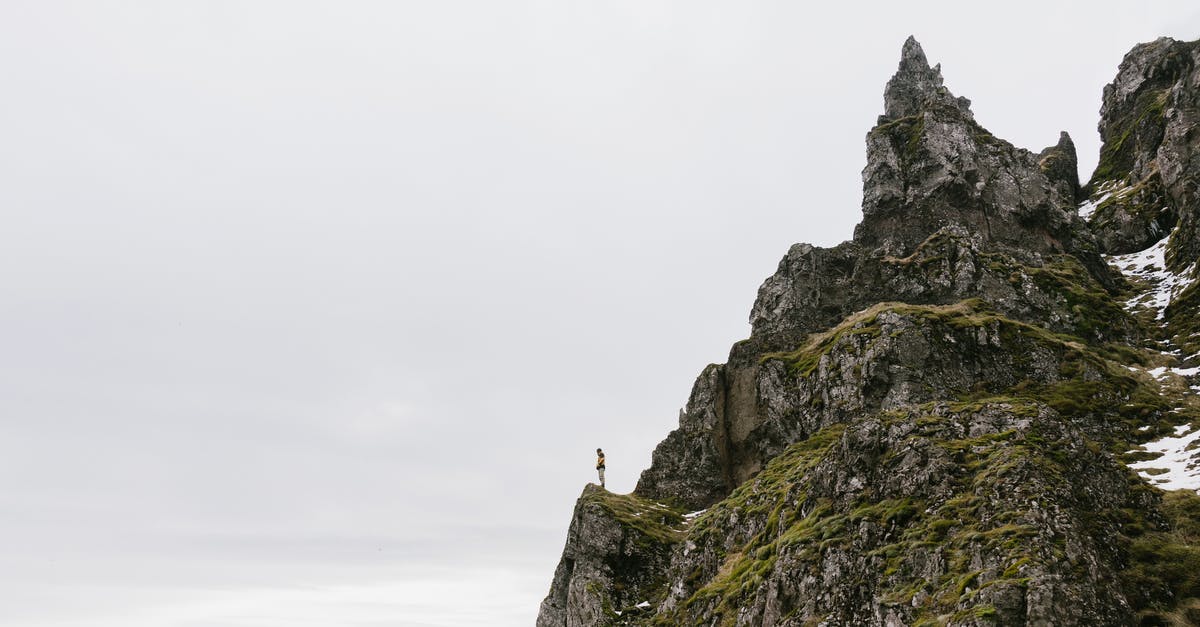How to achieve 3.5m distance between layers in a slime farm? - From below of unrecognizable hiker standing alone on edge of rocky cliff against cloudy sky