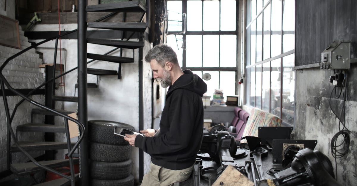 How to apply a useful uniform to my human mercenaries? - Bearded worker using tablet while standing near workbench in workshop